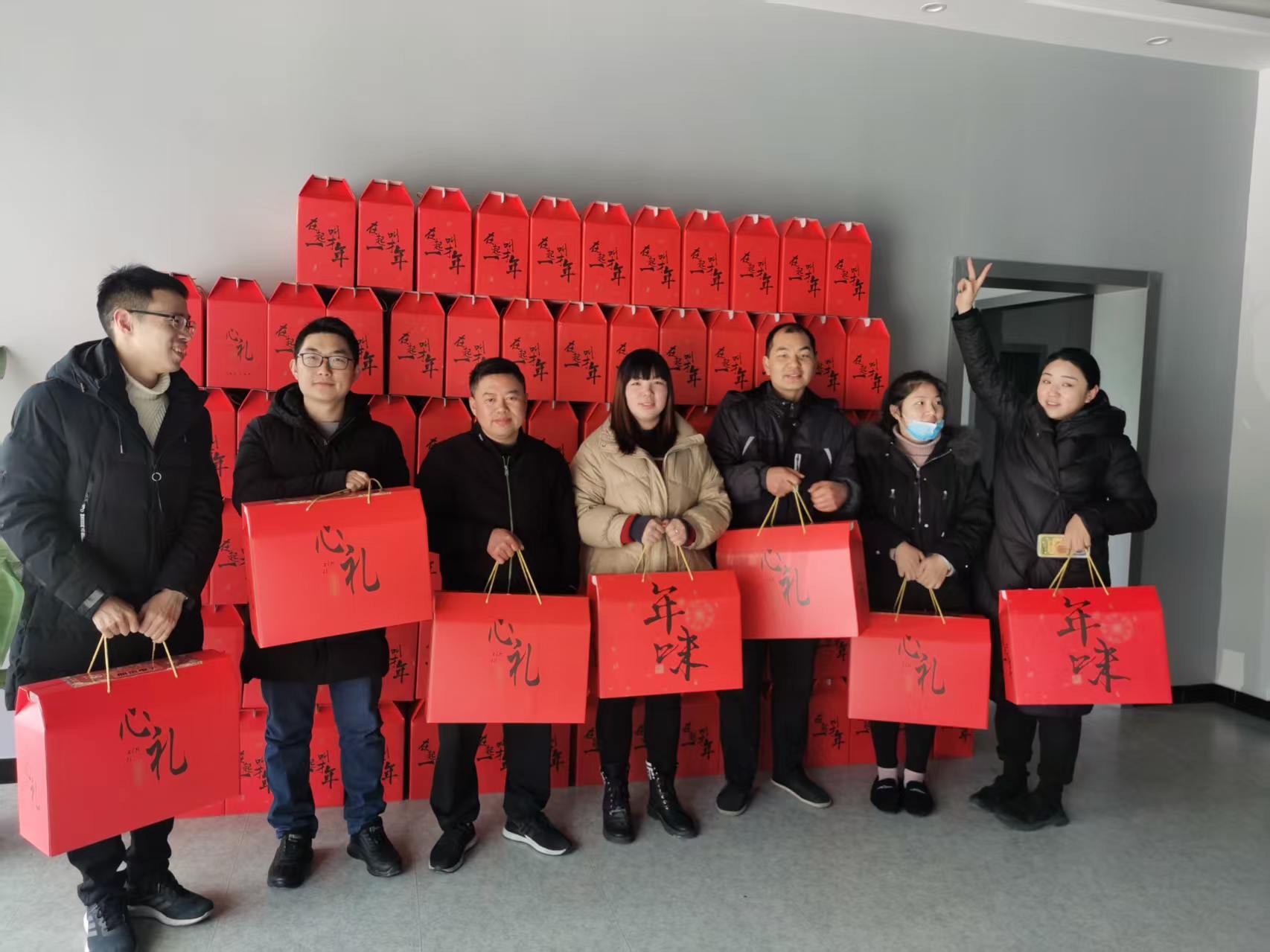Employees posing with red holiday gift boxes