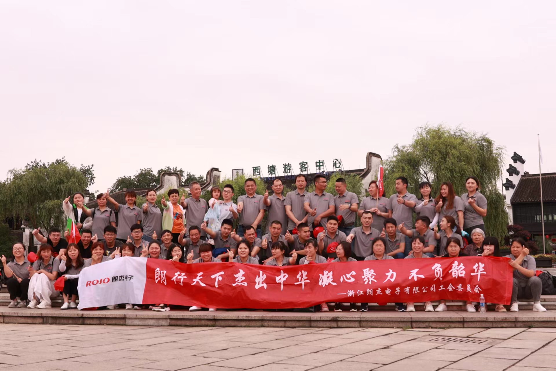 The Langjie team holding a company event banner in front of the Xitang Visitor Center