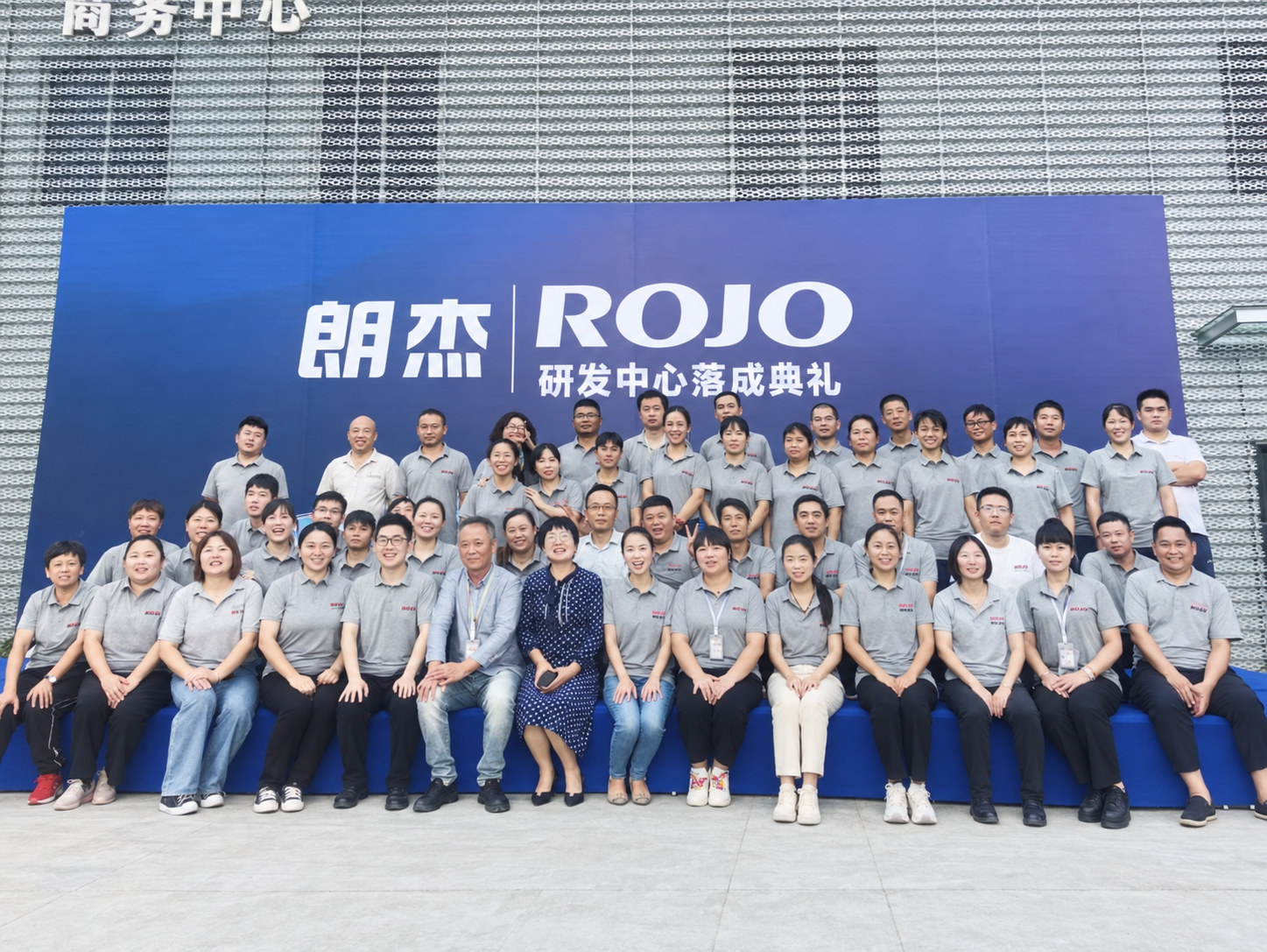 A team photograph in front of a banner for the opening ceremony of Langjie's R&D center