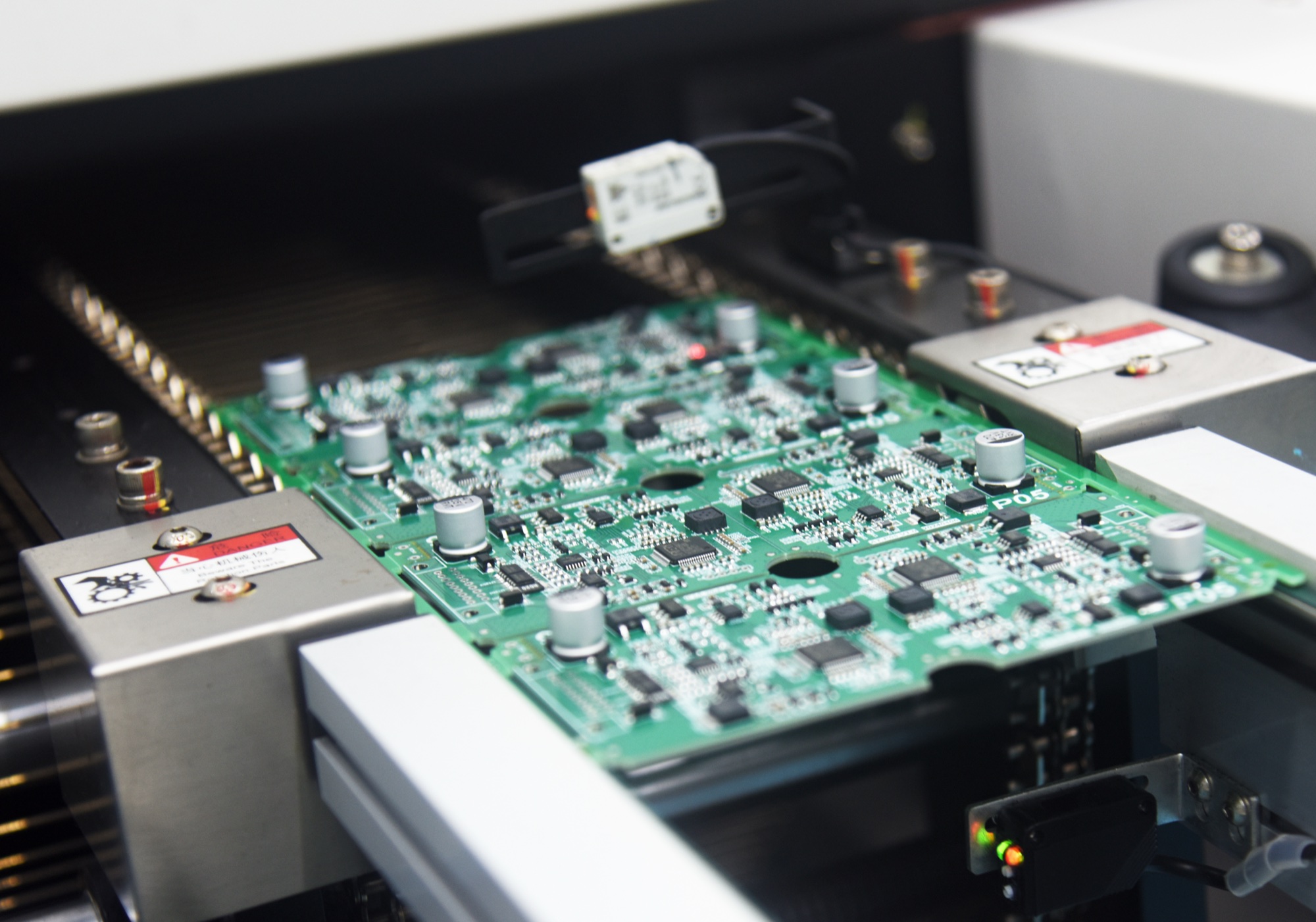 A green circuit board and electronic components on electronics manufacturing equipment